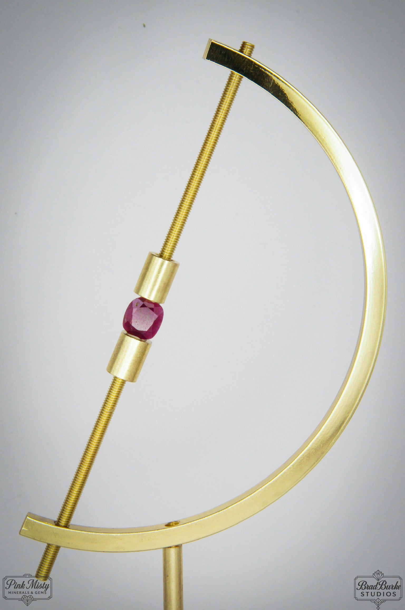 Gold crescent moon-shaped bracelet with a purple gemstone on a gray background